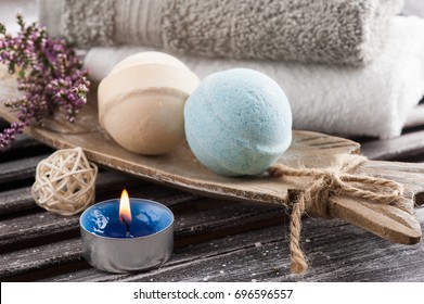 SPA composition with blue vanilla bath bombs, heather flowers, lit candle. Wooden background 
