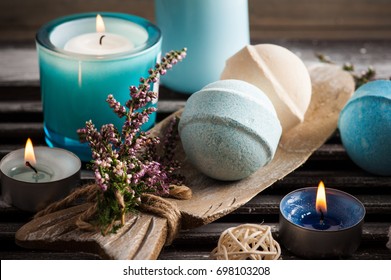 SPA composition with blue vanilla bath bombs, heather flowers, lit candles. Wooden background 