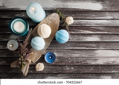 SPA composition with blue vanilla bath bombs, heather flowers, lit candles. Wooden background 