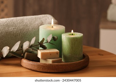 Spa composition. Burning candles, soap, towel and eucalyptus branch on wooden table