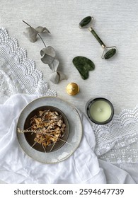 Spa composition with natural elements and textures. Spa setting for a serene beauty routine. Facial massage jade roller, natural brush, containers for storing cosmetics, incense sticks