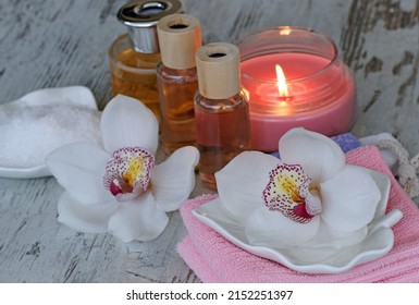 Spa composition with orchid flowers, bottles of aromatic oils and a scented candle.