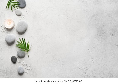 Spa concept on white stone background, palm leaves, candle and zen like grey stones, top view, copy space. - Shutterstock ID 1416502196