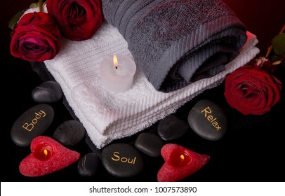 Spa concept in Valentine's Day, red roses, candles in the shape of heart, spa stones with the inscription soul, body, relax