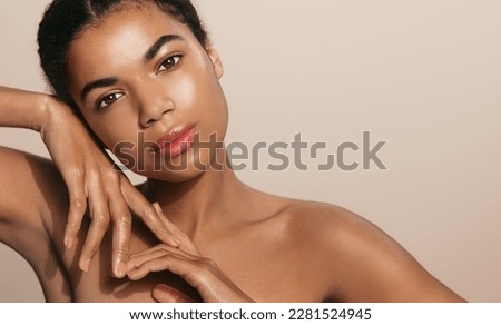 Spa and cosmetics. Young black woman with glowing, clean and natural skin, posing with bare shoulders, face after cleansing gel and skincare routine, standing over brown background.