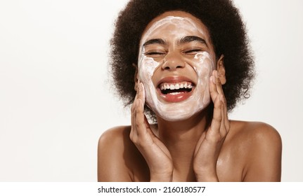 Spa And Cosmetology. Young African American Woman Smiling Happy Laughing While Washing Face, Cleansing Skin, Apply Moisturizing Cream, Face Lotion Or Toner, Pink Background.