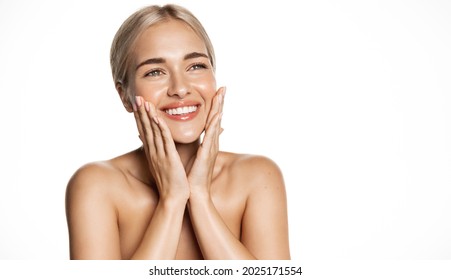 Spa and cosmetology. Young blond woman smiling happy, looking up, holding hands on face, apply moisturizing cream, face lotion or toner, white background - Shutterstock ID 2025171554