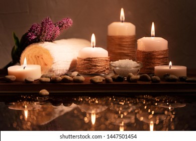 Spa decorative set with sea pebbles, salt, aromatic candles, towel and flower. Golden composition in low key, dark photo with beautiful reflections and bokeh. With space for text. - Powered by Shutterstock