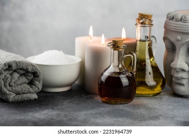 Spa massage relax composition setting. Natural essence oils, sea salt, towel, candles, Buddha head statue on gray background. - Powered by Shutterstock