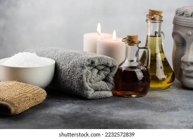 Spa massage relax composition setting. Natural essence oils, sea salt, towel, candles, Buddha head statue on gray background. - Powered by Shutterstock