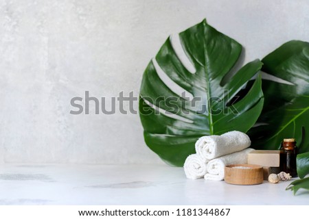 Spa and massage treatments on white, marble background monstera leaves. Flat lay. Top view