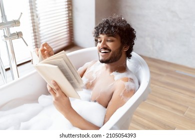 Spa procedure, self care and resting in bathroom. Happy young indian man in bath with foam, reading book in interior in morning, free space - Powered by Shutterstock