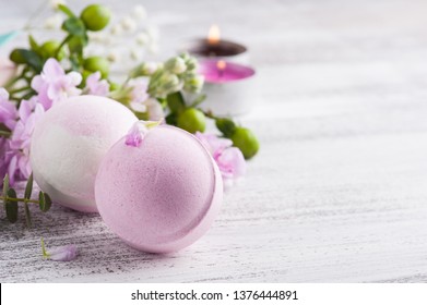 Pflegeprodukte mit Badebomben und Kerzen. Grüne Blumen auf Hintergrund