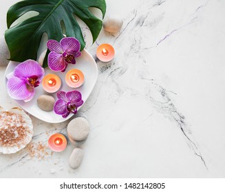Spa products with orchid flowers on a white marble background