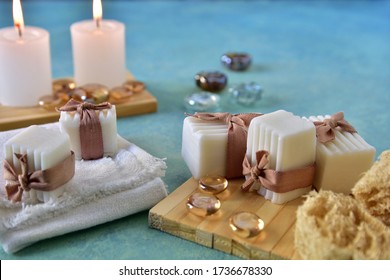 Spa And Relaxation Concept. Bath And Aromatherapy Accessories In Natural Wood Craft Table, Handmade Soap, Sea Sponge, Towel, Lighted Candles And Glass Gems. White, Water Blue, Beige Colors.