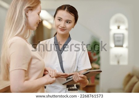 Spa salon administrator asking client to fill form on tablet computer 商業照片 © 