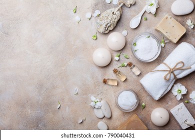 Spa Setting From Body Care And Beauty Treatment Products With Flowers On Stone Background Top View. Healthy And Wellness Concept. Flat Lay Style.