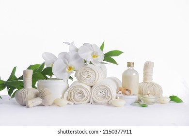 Spa setting with bottles of essential oil , , herbal ,ball,  candle , three rolled towel, candle,, leaves ,orchid 

