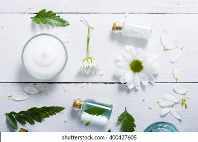 spa setting with cosmetic cream, gel, bath salt and fern leaves on white wooden table background - Powered by Shutterstock