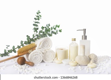 Spa Setting With Eucalyptus Leaves With On Rolled Towel With Oil Bottle ,candle, Herbal Ball On Pile Of White Stones


