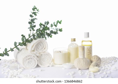 Spa Setting With Eucalyptus Leaves With On Rolled Towel With Oil Bottle ,candle, Herbal Ball On Pile Of White Stones


