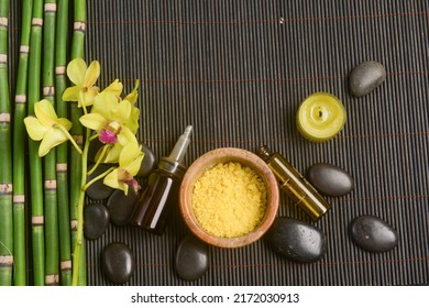 Spa setting with row of bamboo grove ,orchid with oil bottle, candle, stones, with bamboo grove  on bamboo mat.