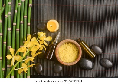 Spa setting with row of bamboo grove ,orchid with oil bottle, candle, stones, with bamboo grove  on bamboo mat.

