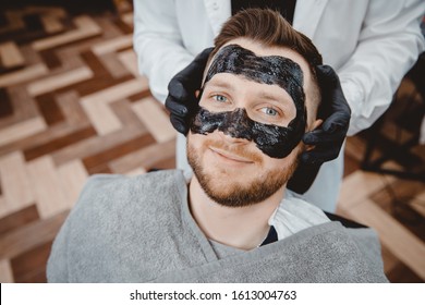 Spa And Skin Care For Men. Barber Professional Applies Black Charcoal Mask To Client Man.