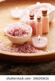 Spa still life with pink sea salt and flower petals on wooden background - Shutterstock ID 246243616