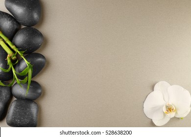 Spa stones, bamboo branch and orchid flower on color background
