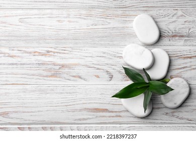 Spa Stones And Bamboo Leaves On White Wooden Table, Flat Lay. Space For Text