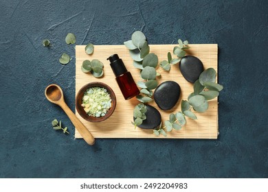 Spa stones, bamboo mat and bottle of eucalyptus essential oil on dark blue background - Powered by Shutterstock