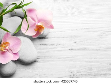 Spa stones, bamboo stack and orchid flowers on wooden background