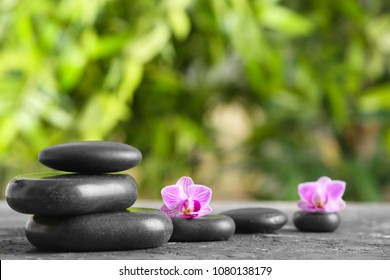 Spa stones with beautiful flowers on table outdoors
