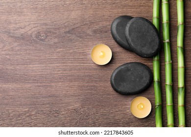 Spa Stones, Burning Candles And Bamboo Stems On Wooden Table, Flat Lay. Space For Text