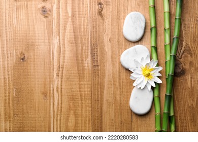 Spa Stones, Flower And Bamboo Stems On Wooden Table, Flat Lay. Space For Text