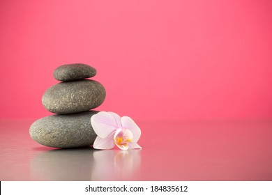 Spa Stones On Pink Background With Orchids.