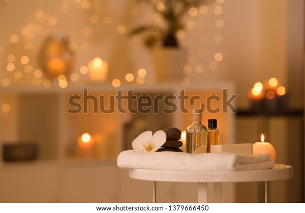 Spa supplies, burning candle and flower on table\
in beauty salon, space for\
text