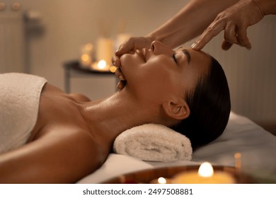 Spa therapist making relaxing facial and head massage for young lady, touching and rubbing her forehead at luxury beauty salon interior - Powered by Shutterstock