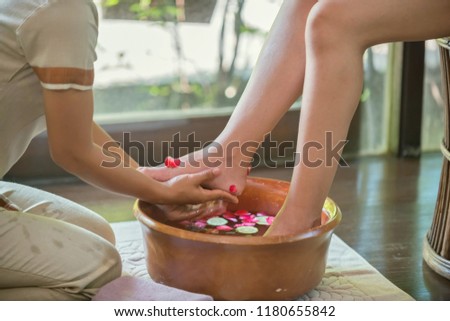 Spa therapy, female feet at spa procedure by therapist
Women's feet soaked in a bowl with water and flower therapy