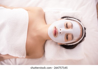 Spa Therapy For Young Asian Woman Receiving Facial Mask At Beauty Salon.