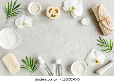 Spa Treatment Concept. Natural/Organic Spa Cosmetics Products, Sea Salt, Massage Brush, Tropic Palm Leaves On Gray Marble Table From Above. Spa Background With A Space For A Text, Flat Lay, Top View