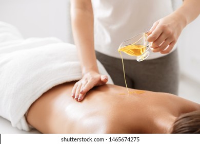 Spa Treatment. Masseur Pouring Aroma Oil On Female Back, Doing Massage