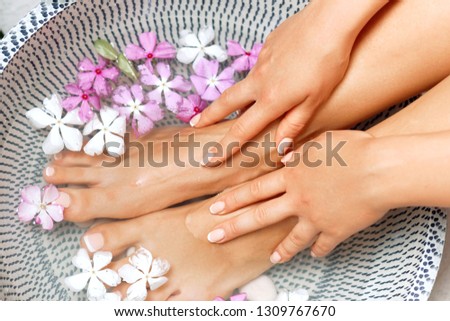 Spa treatment and product for female feet and foot spa. Foot bath in bowl with tropical flowers, Thailand. Healthy Concept. Beautiful female feet, legs at spa salon on pedicure procedure.