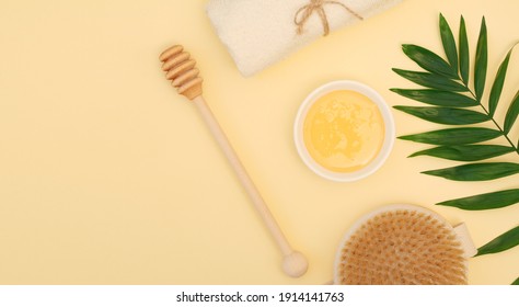 Spa Treatments At Home With Natural Honey And A Dry Body Massage Brush. The Concept Of Personal Care, Weight Loss, Beauty. Anti-cellulite Body Treatments On A Yellow Background. Banner, Flat Lay, Top