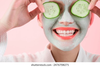 Spa treatments and wellness. Beautiful woman with facial cosmetic mask on face holds slices of fresh cucumber. Beauty and skin care. Spa salon, anti-aging mask, cosmetology concept. Closeup portrait - Powered by Shutterstock