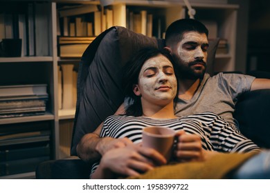 spa weekend. couple with applied cosmetic face mask on their faces, relaxing sofa at their home. evening scene - Powered by Shutterstock