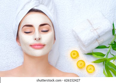 Spa Woman applying Facial clay Mask. Beauty Treatments. Close-up portrait of beautiful girl with a towel on her head applying facial mask. - Shutterstock ID 626152427
