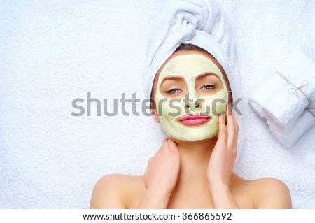 Spa Woman applying Facial clay Mask. Beauty Treatments. Close-up portrait of beautiful girl with a towel on her head applying facial mask