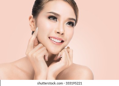 Spa Woman Portrait. Beautiful Asian Girl Touching her Face. Perfect Fresh Skin. Pure Beauty Model Female looking at camera. Youth and Skin Care Concept.on pink background with clipping path.